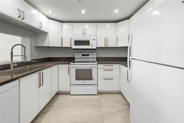 a kitchen with granite countertop white cabinets and white appliances