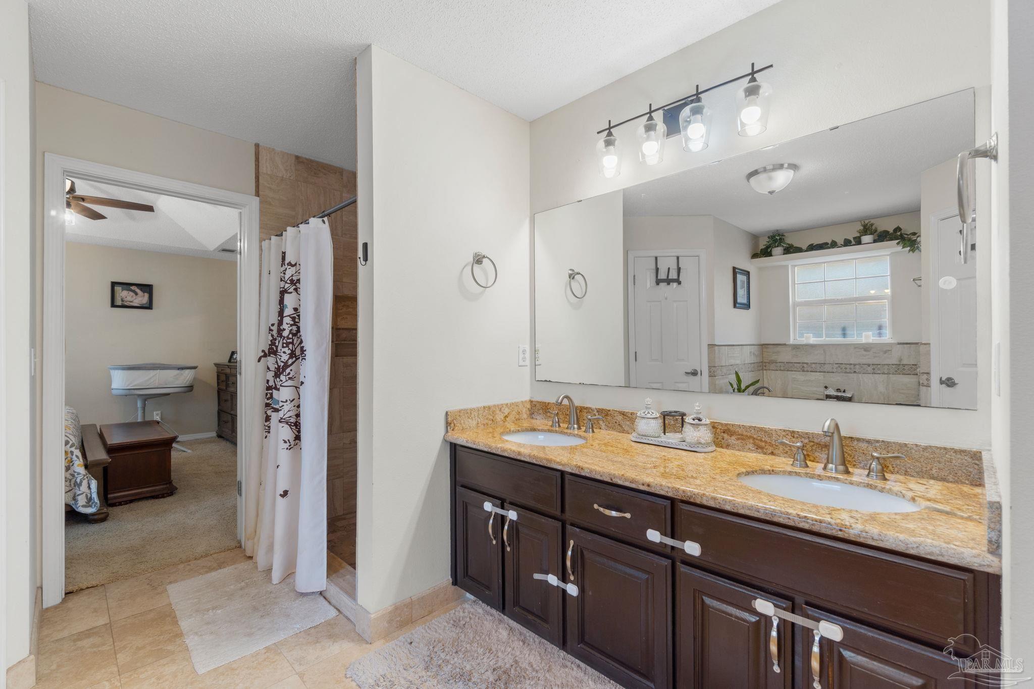 8046 Castle Pointe Way Pensacola, FL 32506 - Photo 25 of 40 a bathroom with a granite countertop double vanity sink and mirror