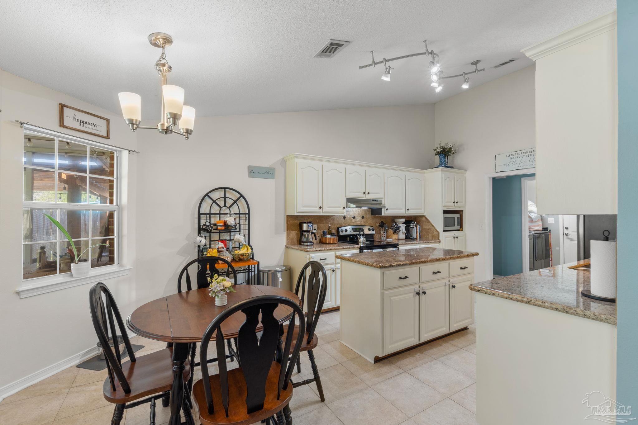 8046 Castle Pointe Way Pensacola, FL 32506 - Photo 10 of 40 a kitchen with stainless steel appliances a dining table chairs and white cabinets
