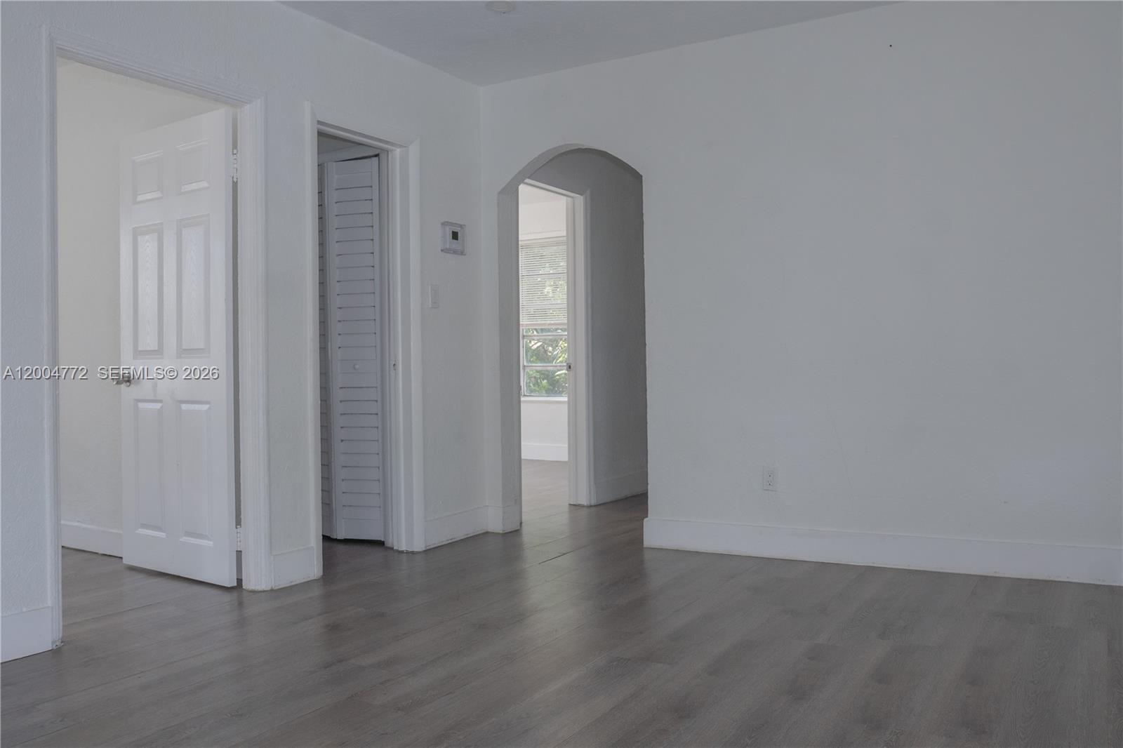 3376 Northwest 49th Street Miami, FL 33142 - Photo 4 of 17 an empty room with wooden floor and mirror