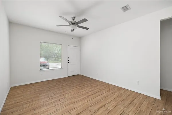 a view of an empty room with wooden floor and a window