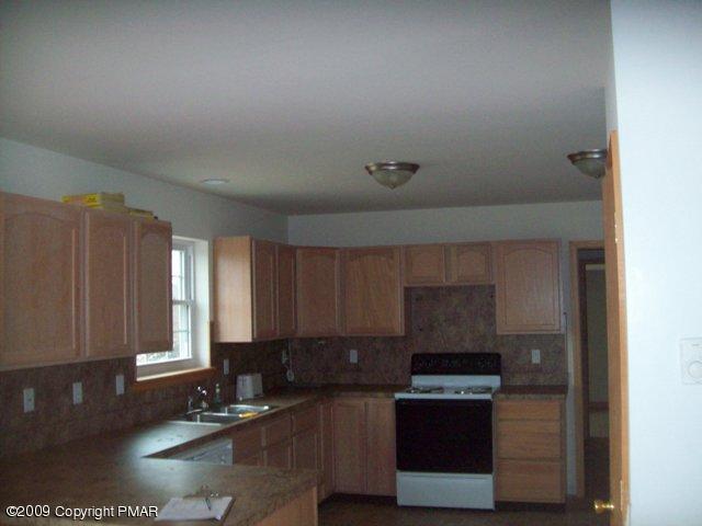 1815 Clover Road South Long Pond, PA 18334 - Photo 3 of 7 a kitchen with a stove a microwave and wooden cabinets
