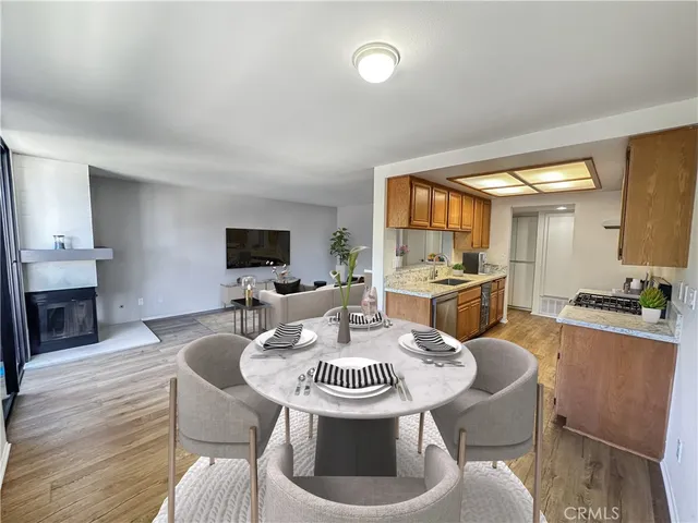 a kitchen with stainless steel appliances kitchen island granite countertop a dining table chairs and a refrigerator