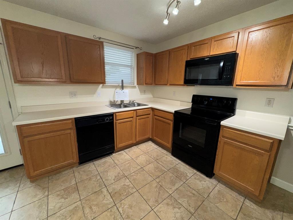 2024 Brazos Court Grand Prairie, TX 75052 - Photo 14 of 40 a kitchen with a sink a stove top oven and wooden cabinetry