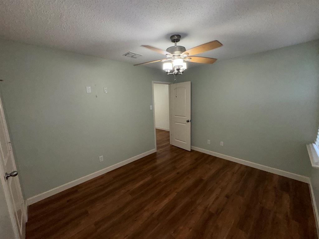 2024 Brazos Court Grand Prairie, TX 75052 - Photo 24 of 40 an empty room with a chandelier fan and wooden floor