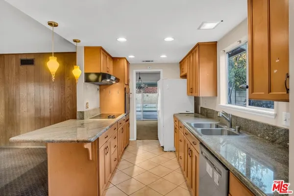 a kitchen with granite countertop a sink stove and refrigerator