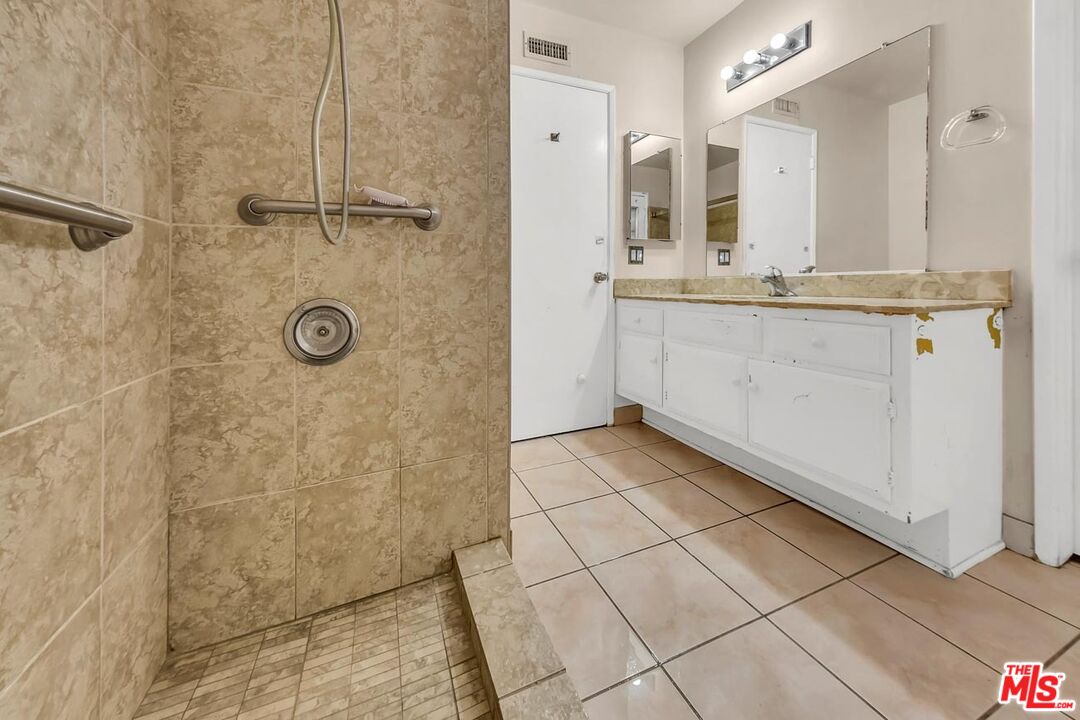 11258 Yolanda Avenue Porter Ranch, CA 91326 - Photo 40 of 46 a bathroom with a granite countertop sink a mirror and shower