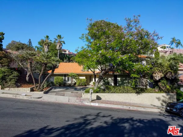 a front view of a house with a yard and tree s