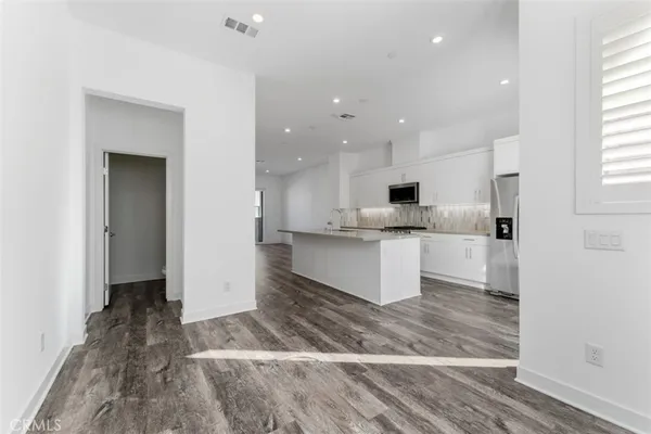 a view of a kitchen with wooden floor and electronic appliances