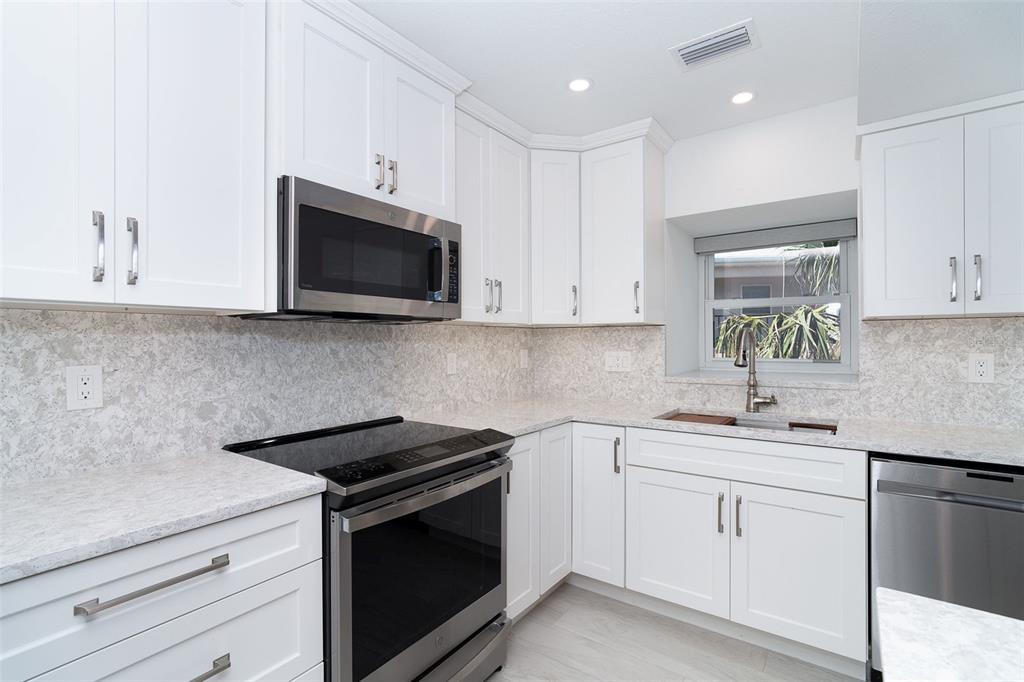 2700 North Beach Road, Unit A201 Englewood, FL 34223 - Photo 6 of 55 a kitchen with white cabinets and white appliances