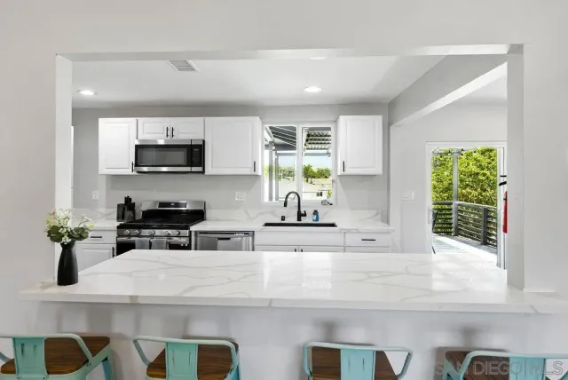 a kitchen with appliances a sink a counter top space cabinets and a window