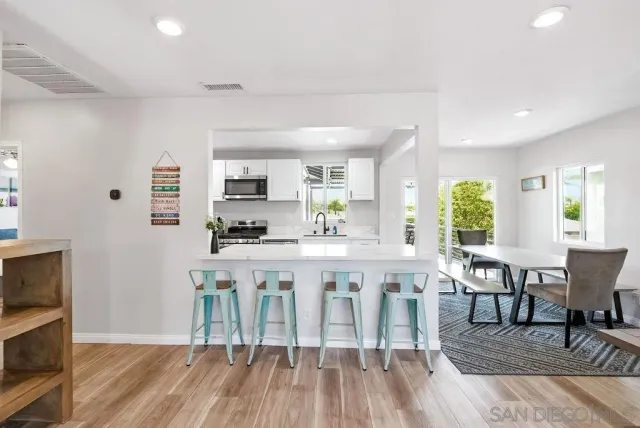 a living room with stainless steel appliances granite countertop furniture wooden floor and a kitchen view