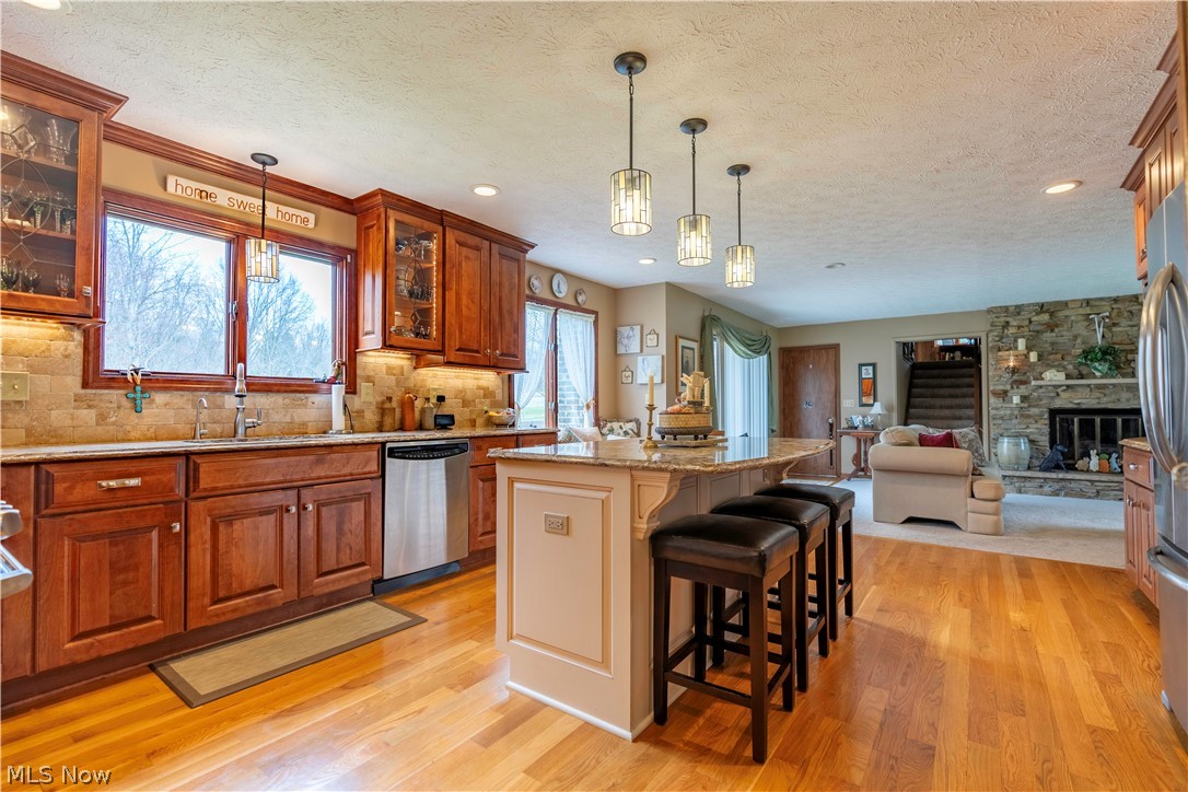 585 Yager Road Clinton, OH 44216 - Photo 13 of 35 Kitchen with a breakfast bar, stainless steel appliances, a kitchen island, hanging light fixtures, and a stone fireplace