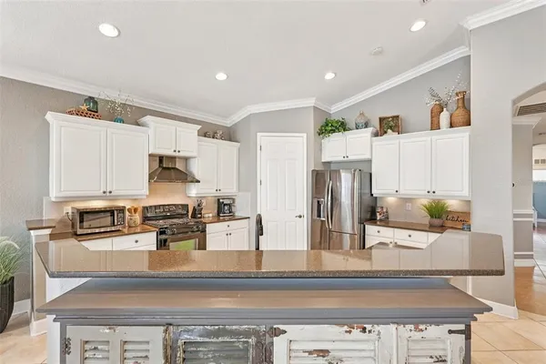 a kitchen with stainless steel appliances kitchen island granite countertop a stove a sink and a refrigerator