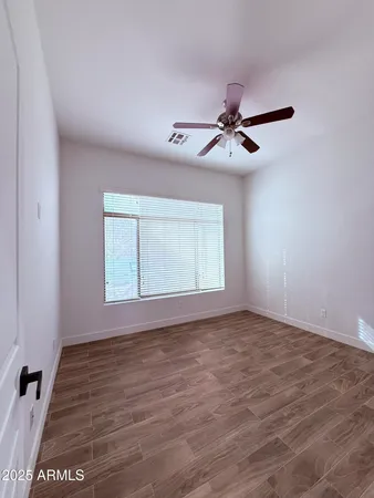 a view of empty room with wooden floor and fan