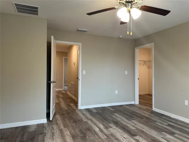an empty room with wooden floor chandelier fan and closet area