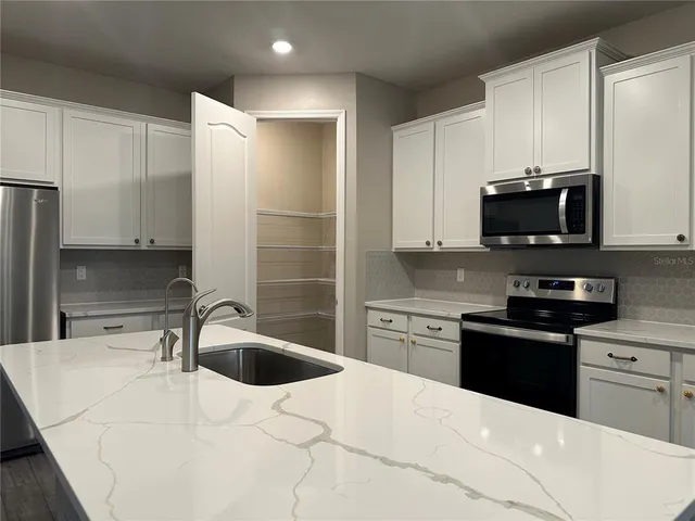 a kitchen with stainless steel appliances a stove a sink a microwave a refrigerator and cabinets