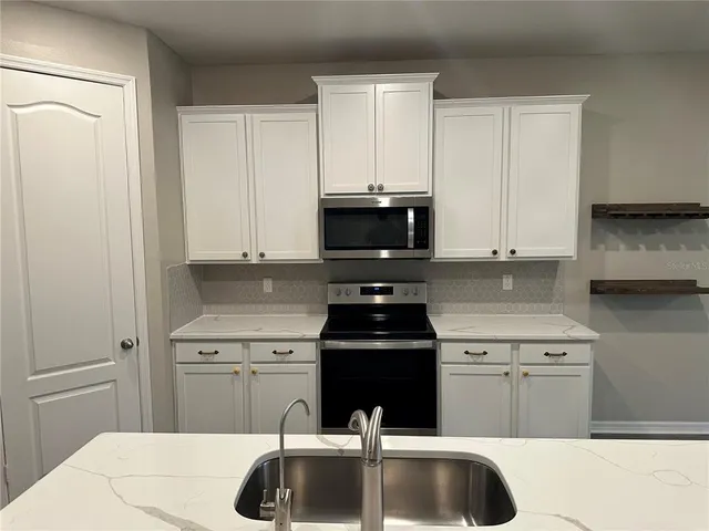 a kitchen with sink a microwave and cabinets