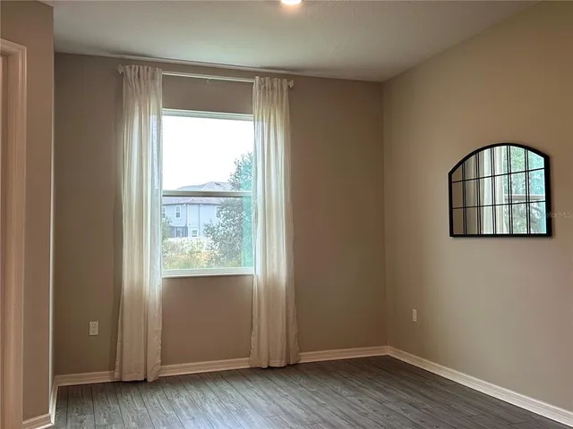 an empty room with wooden floor cabinet and windows