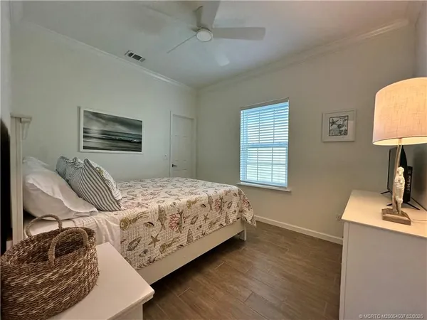 a bedroom with a bed a couch and a dresser with wooden floor