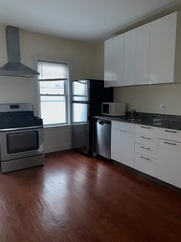 a kitchen with granite countertop a stove a sink and a refrigerator