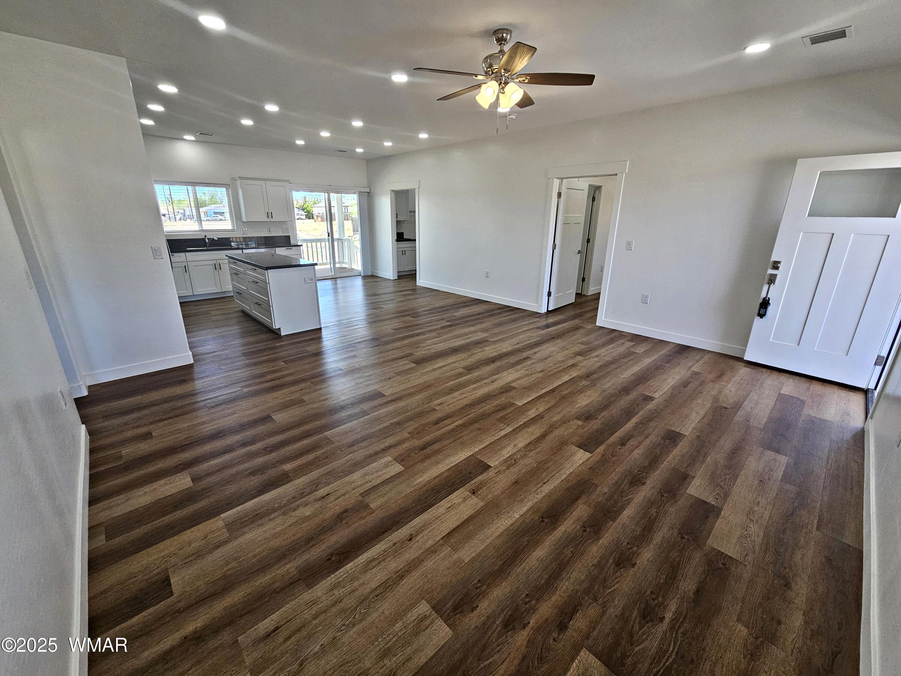 759 South 5th W Street Snowflake, AZ 85937 - Photo 6 of 18 an empty room with wooden floor ceiling fan and kitchen view
