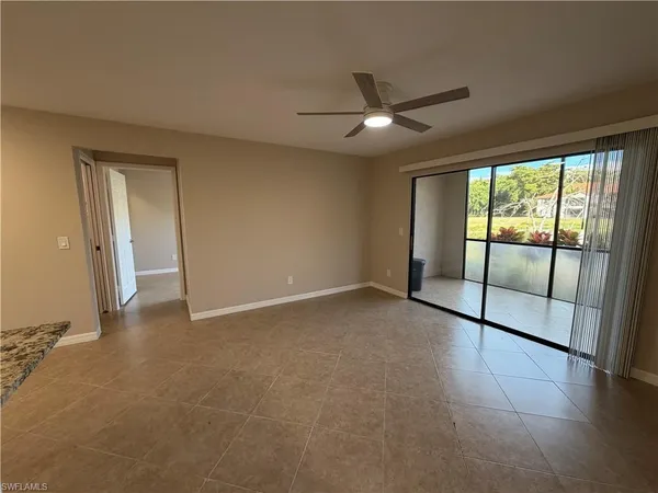 an empty room with sliding glass door and a chandelier fan