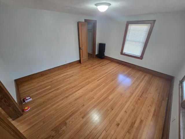 an empty room with wooden floor and mirror