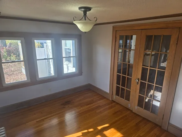 a view of empty room with wooden floor and fan