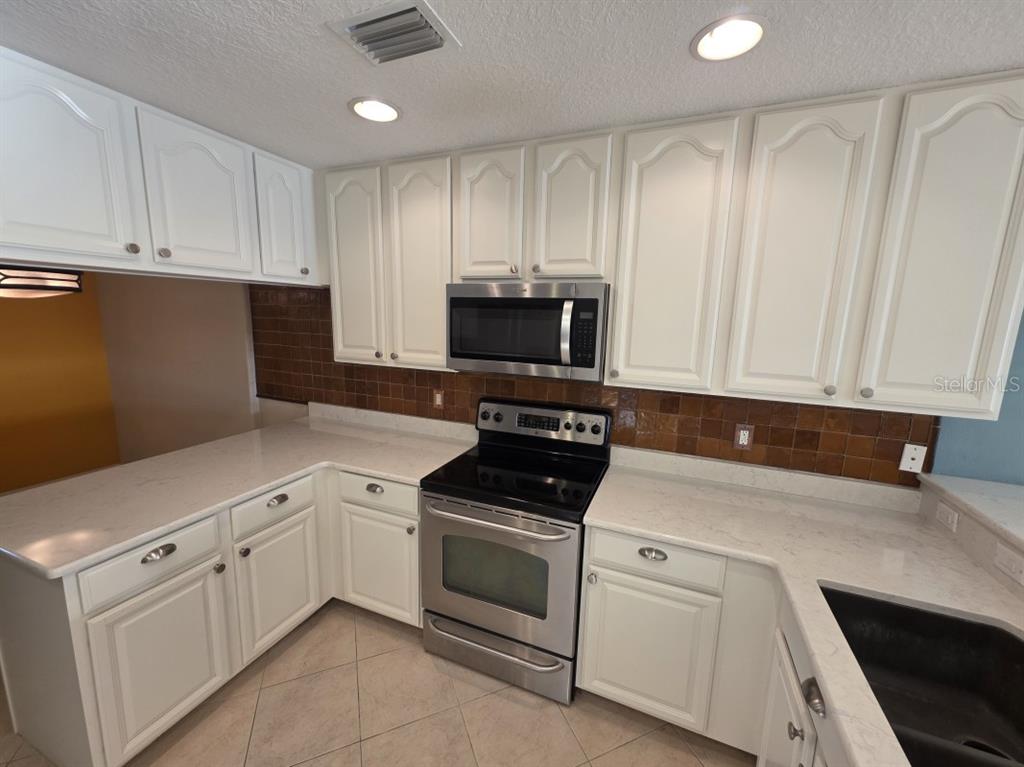7070 Key Haven Road, Unit 402 Seminole, FL 33777 - Photo 12 of 34 a kitchen with white cabinets and white appliances