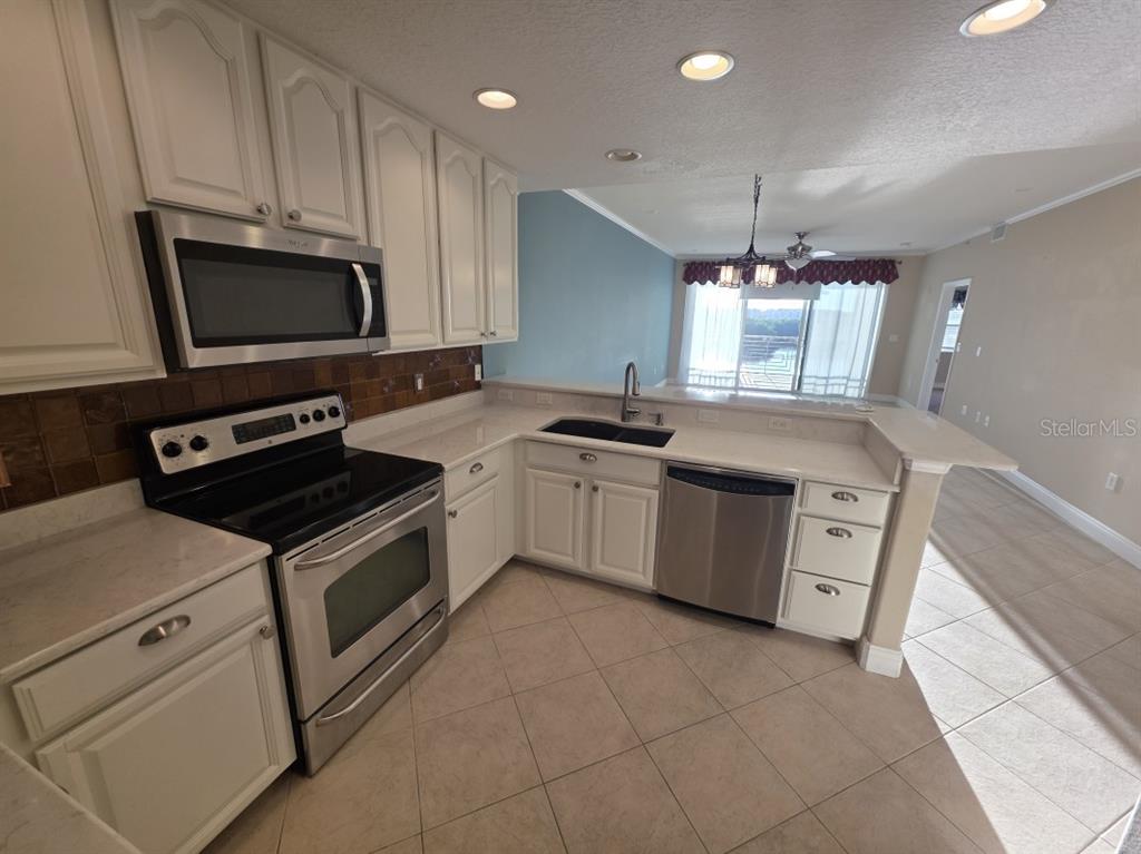 7070 Key Haven Road, Unit 402 Seminole, FL 33777 - Photo 14 of 34 a kitchen with a stove sink and a microwave