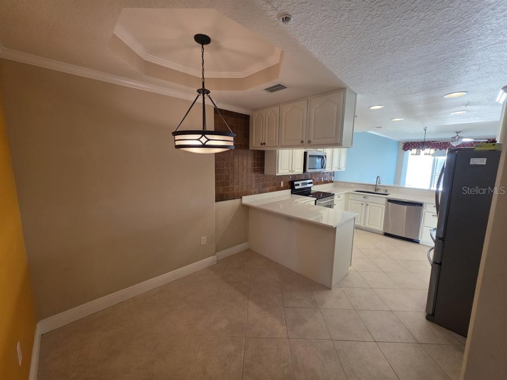 7070 Key Haven Road, Unit 402 Seminole, FL 33777 - Photo 15 of 34 a kitchen with stainless steel appliances granite countertop a sink a stove a refrigerator cabinets a dining table and chairs