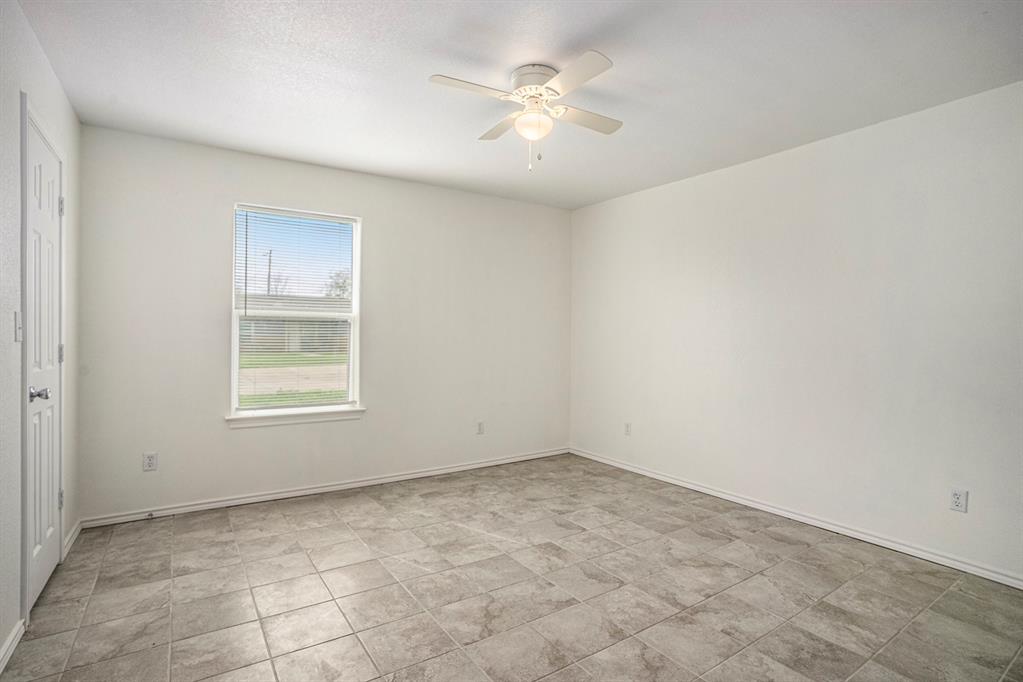 405 North Cleburne Whitney Road Rio Vista, TX 76093 - Photo 12 of 23 Room featuring light-toned tile flooring, a window with white trim, and a ceiling fan with integrated lighting