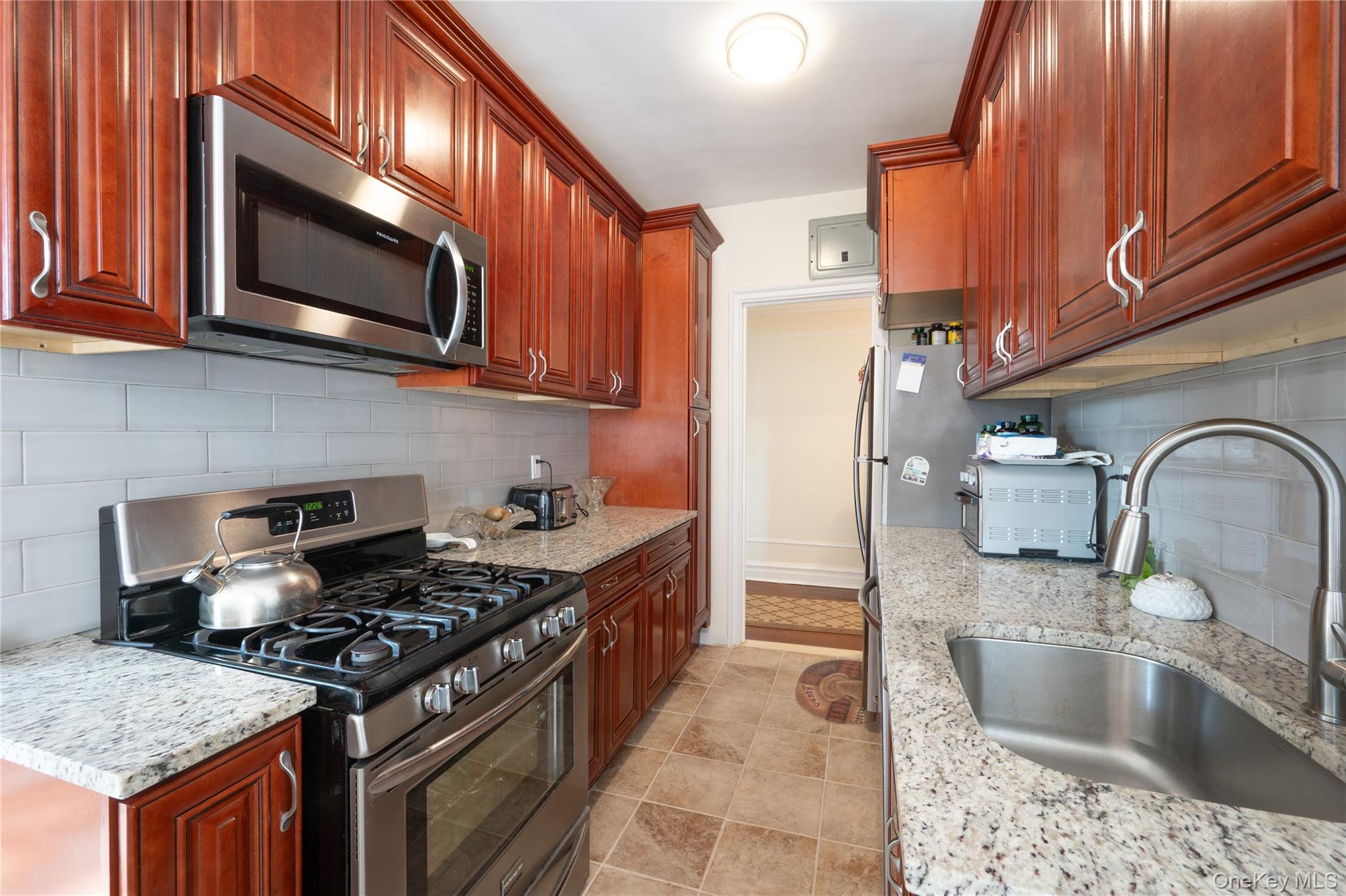 1468 Midland Avenue, Unit 4D Bronxville, NY 10708 - Photo 12 of 24 Kitchen with appliances with stainless steel finishes, tasteful backsplash, light stone counters, and light tile patterned flooring