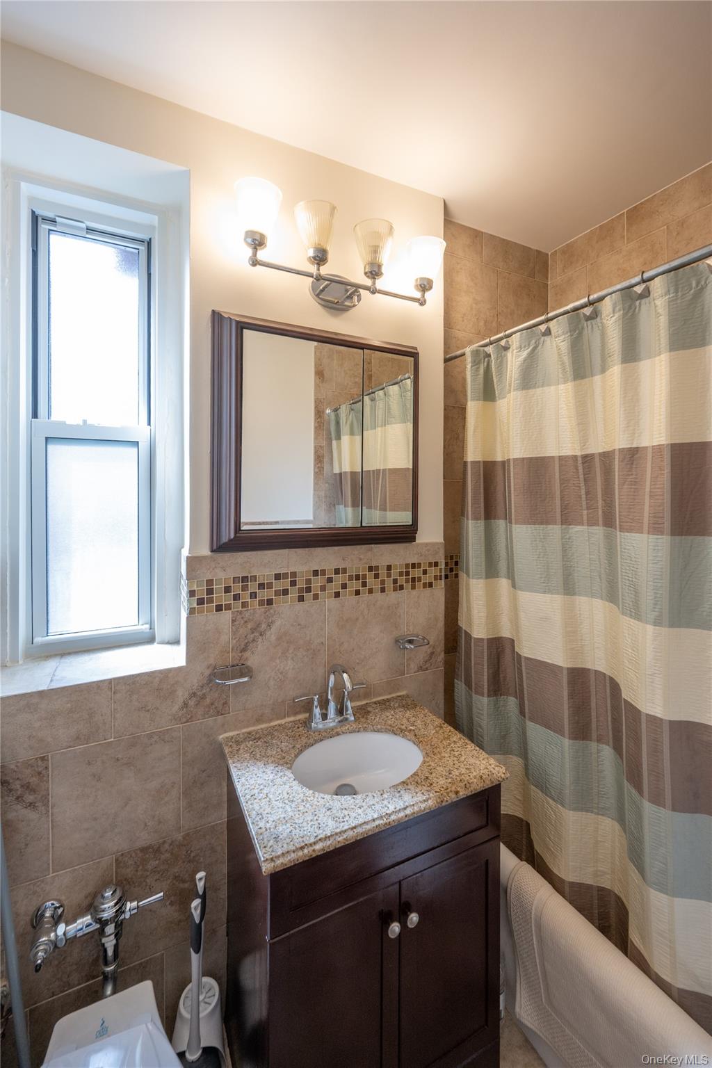 1468 Midland Avenue, Unit 4D Bronxville, NY 10708 - Photo 16 of 24 Bathroom featuring tile walls, a shower with shower curtain, vanity, and tasteful backsplash