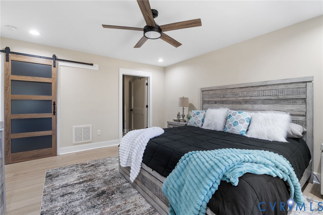 13545 Prince George Drive Disputanta, VA 23842 - Photo 9 of 18 Bedroom with a barn door, light wood finished floo