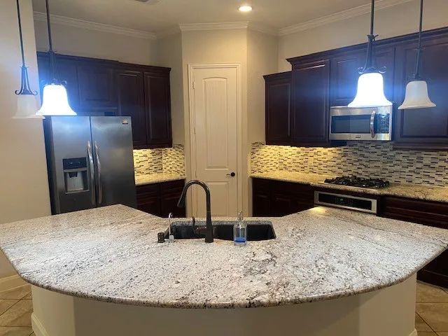 a kitchen with kitchen island granite countertop a sink and refrigerator