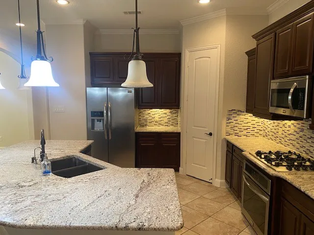 a kitchen with stainless steel appliances granite countertop a sink a stove and a refrigerator