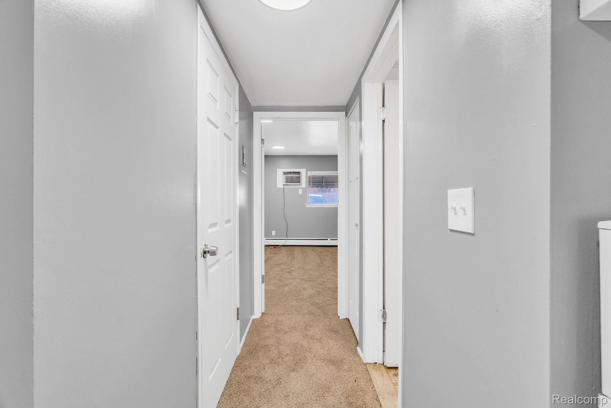 4535 Cadieux Road, Unit 42 / 210 Detroit, MI 48224 - Photo 12 of 16 Corridor with light carpet, baseboard heating, and an AC wall unit