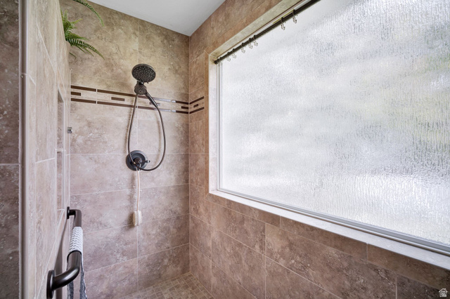2139 Village Point Way Sandy, UT 84093 - Photo 15 of 35 Primary bath shower with floor-to-ceiling textured tile, decorative tile band, built-in recessed shelving, a wide privacy window, and a matte black shower fixture