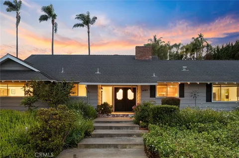 a front view of a house with a yard and potted plants
