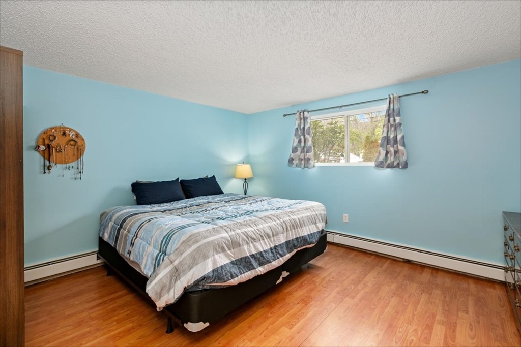 25 Clark's Road, Unit 101 Amesbury, MA 01913 - Photo 14 of 32 a bedroom with a bed and wooden floor