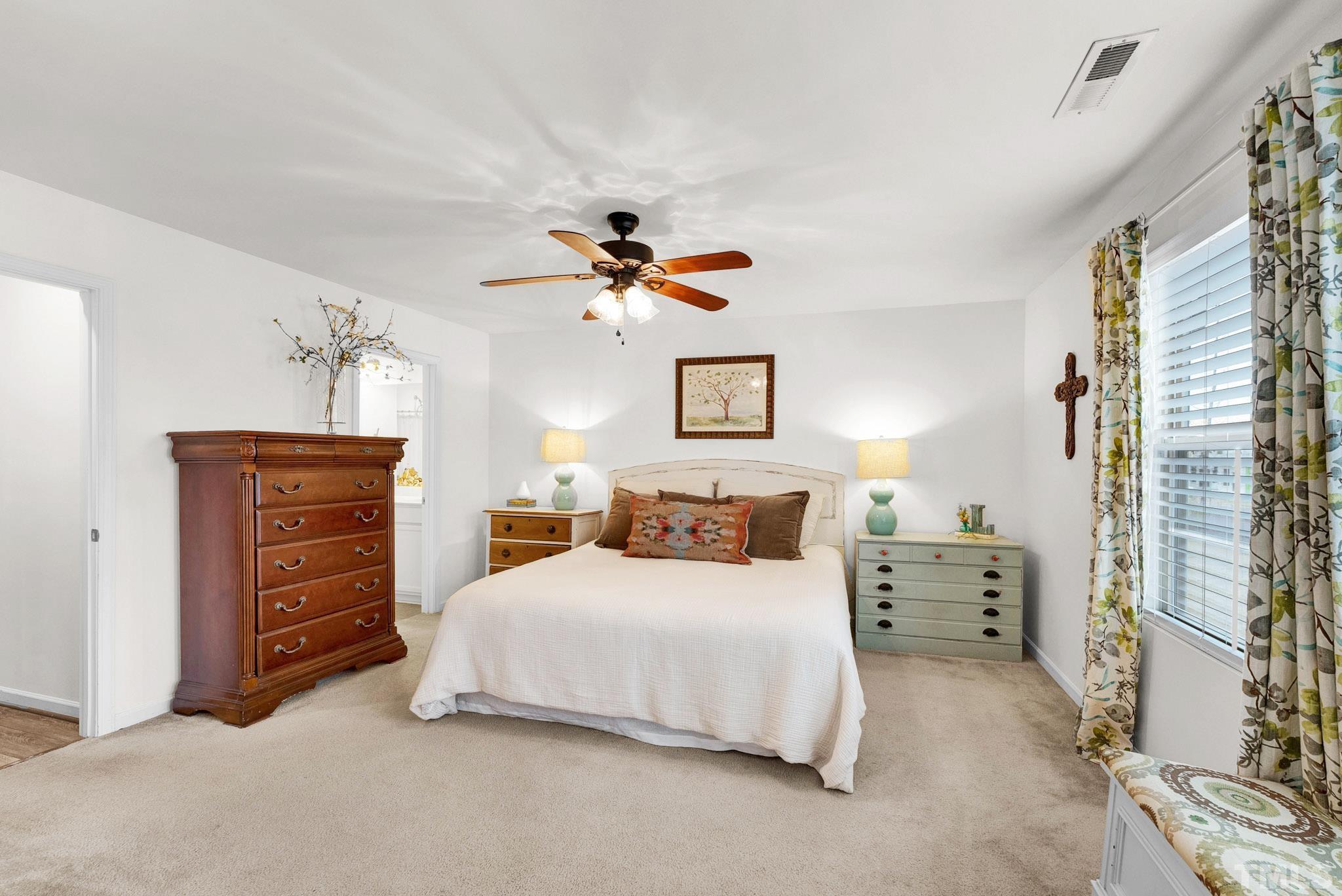 1004 Grand Ridge Drive Rolesville, NC 27571 - Photo 14 of 24 a bedroom with a bed a chandelier and a dresser