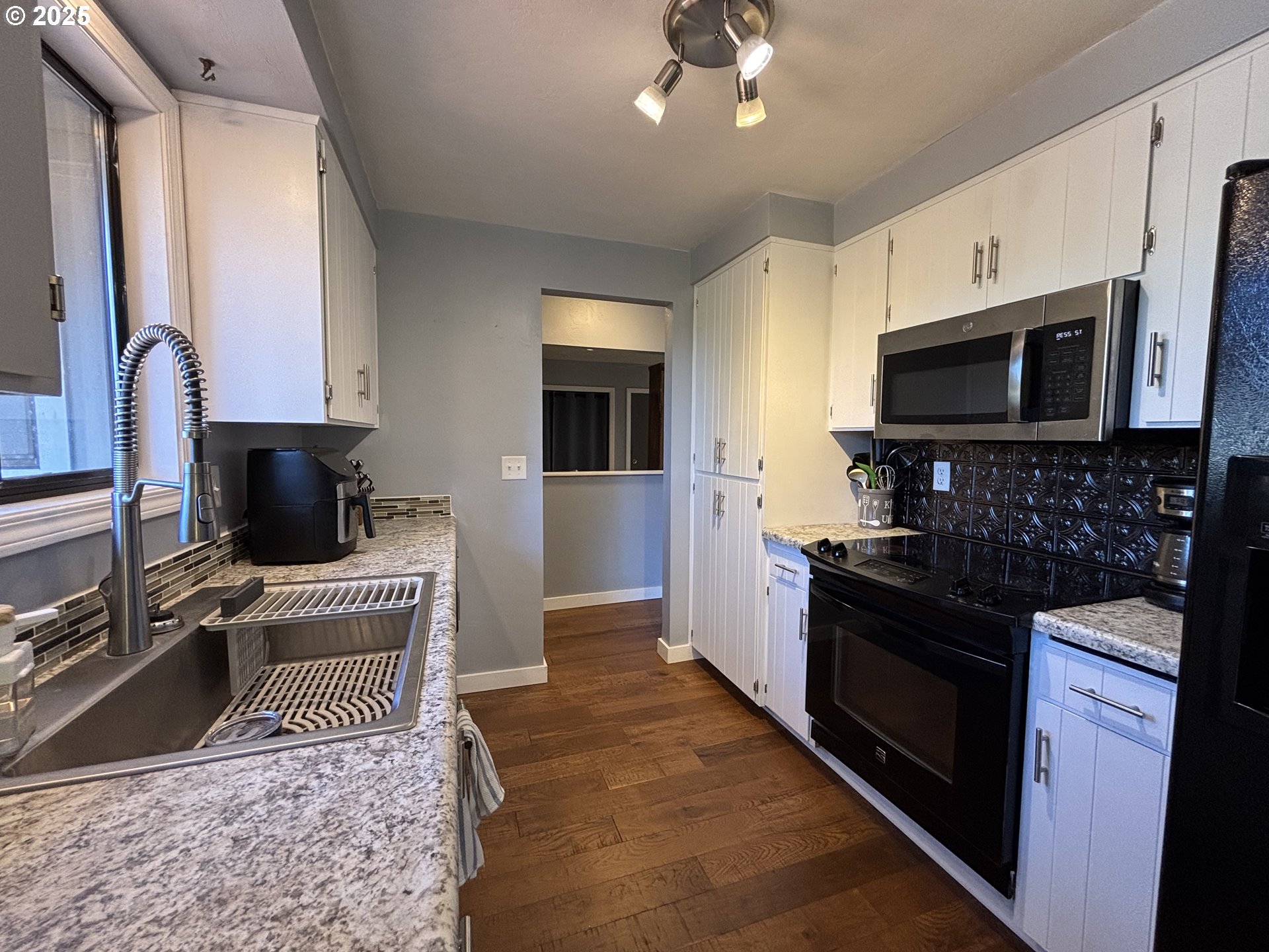 7066 Aster Street Springfield, OR 97478 - Photo 18 of 46 a kitchen with stainless steel appliances granite countertop a refrigerator a stove a sink and a microwave