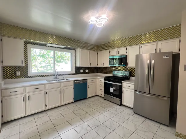 a kitchen with granite countertop cabinets stainless steel appliances a sink and a window