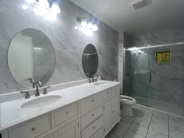 a bathroom with a double vanity sink toilet and a mirror