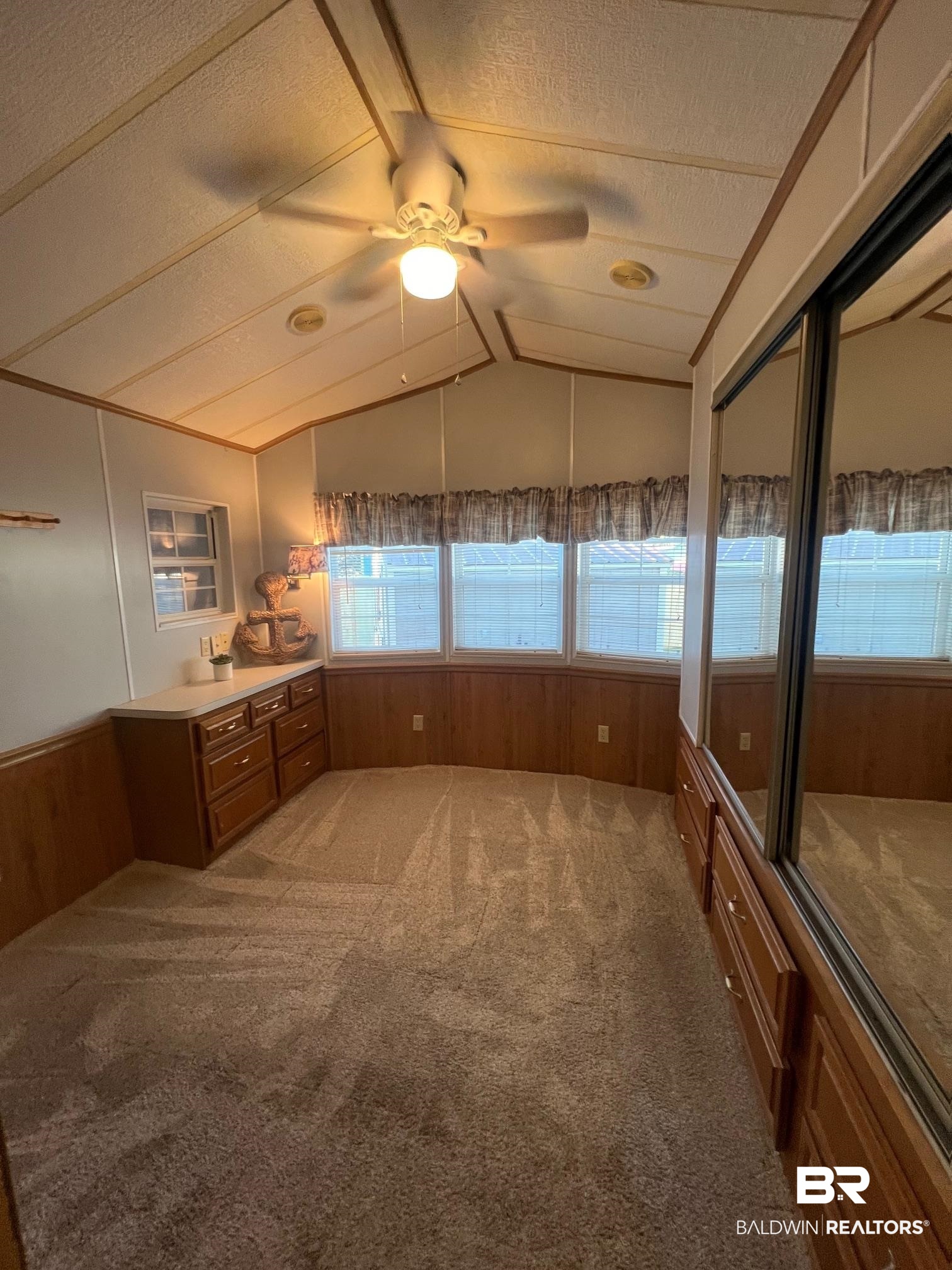 698 Escambia Loop Lillian, AL 36549 - Photo 7 of 16 Unfurnished bedroom featuring ceiling fan, wooden walls, carpet, a closet, and vaulted ceiling