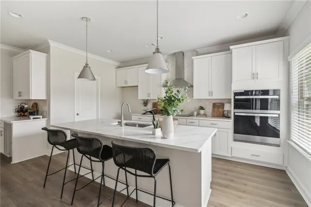 a kitchen with stainless steel appliances kitchen island granite countertop a table chairs stove and white cabinets