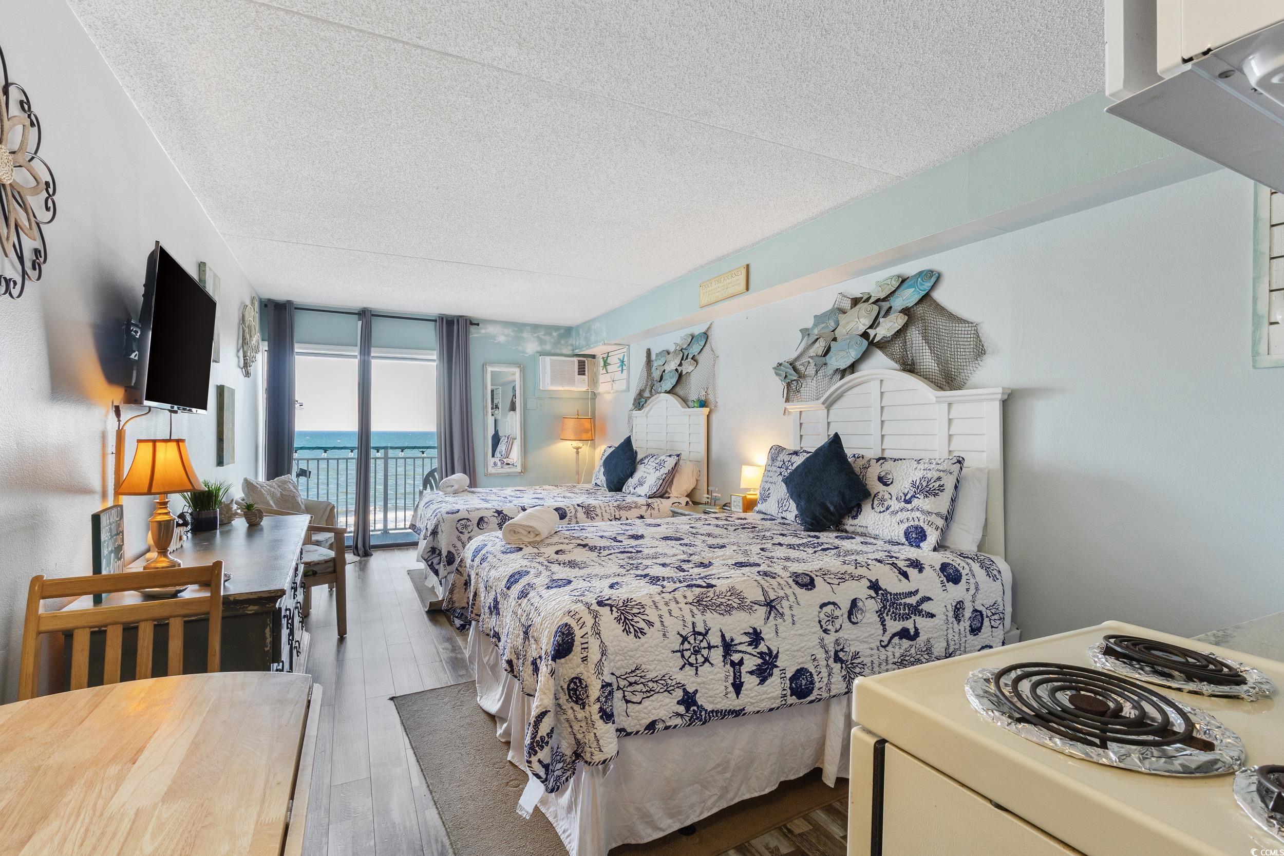 1207 South Ocean Boulevard, Unit 20603 Myrtle Beach, SC 29577 - Photo 3 of 19 Bedroom with a wall of windows, a textured ceiling, access to outside, dark wood-style flooring, and a wall unit AC