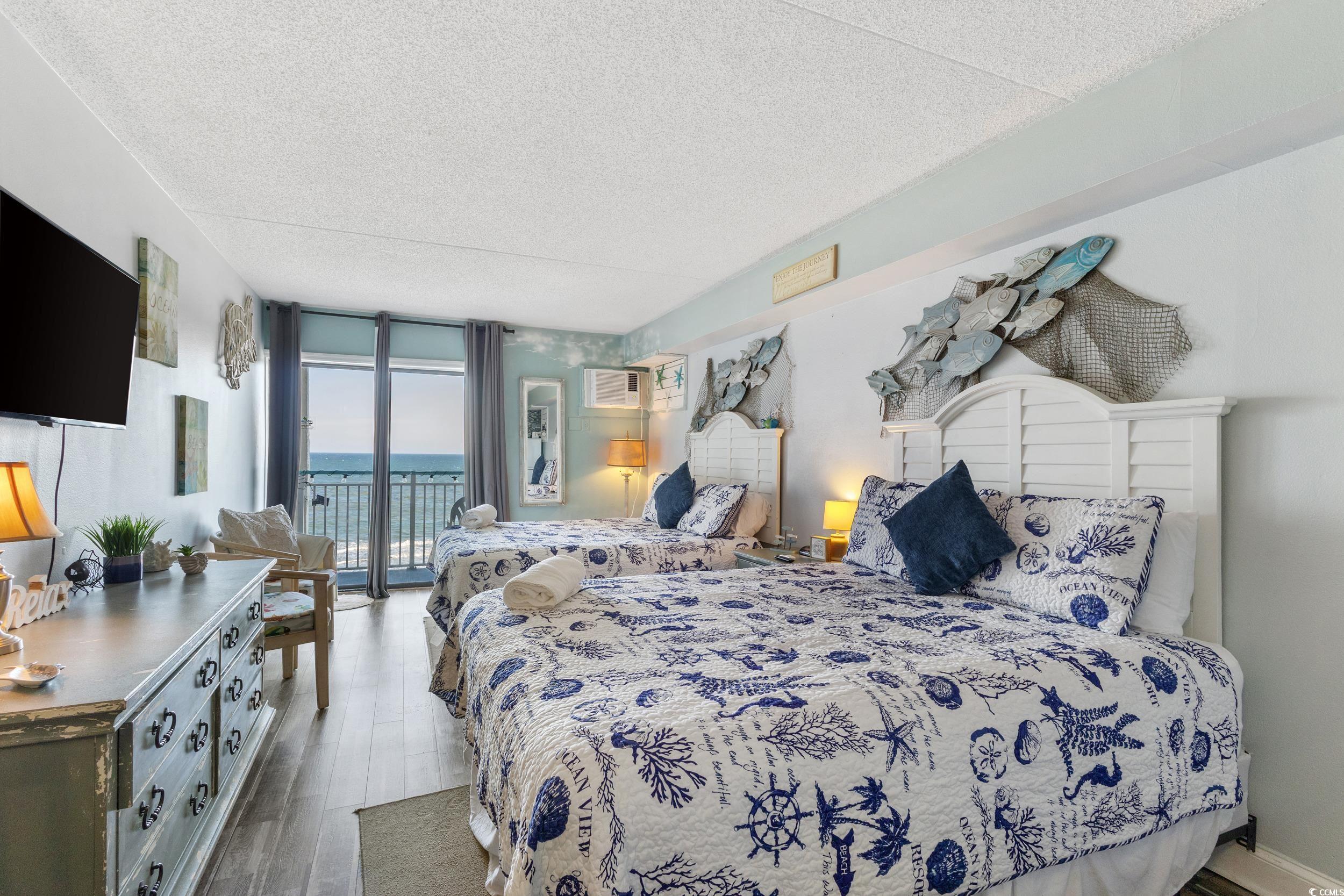 1207 South Ocean Boulevard, Unit 20603 Myrtle Beach, SC 29577 - Photo 6 of 19 Bedroom with expansive windows, a textured ceiling, access to exterior, wood finished floors, and a wall mounted AC